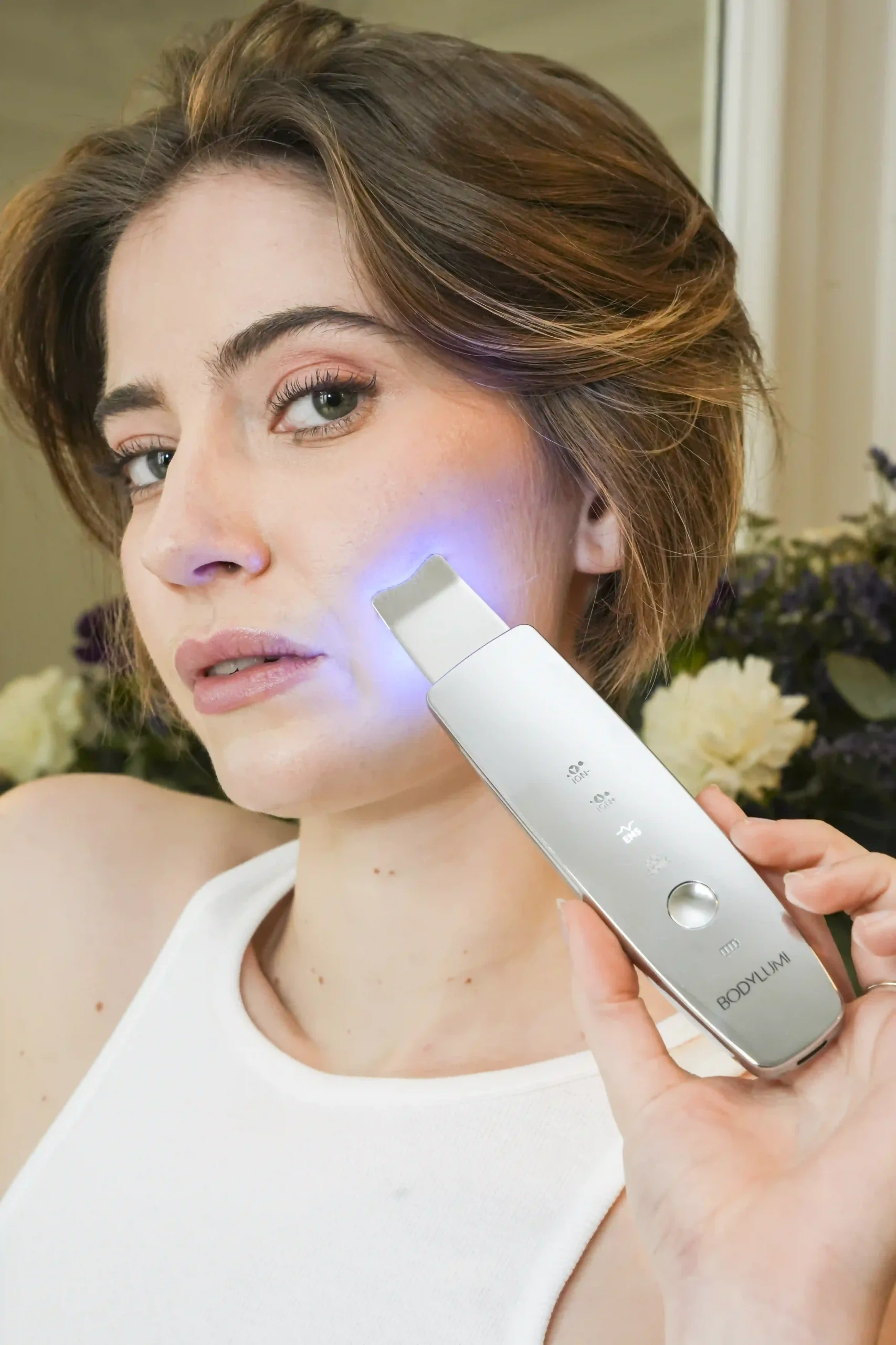 Une femme tient l'appareil ultrasonique bodylumi paris pour un nettoyage doux et en profondeur. La peau est visiblement saine et lumineuse.
